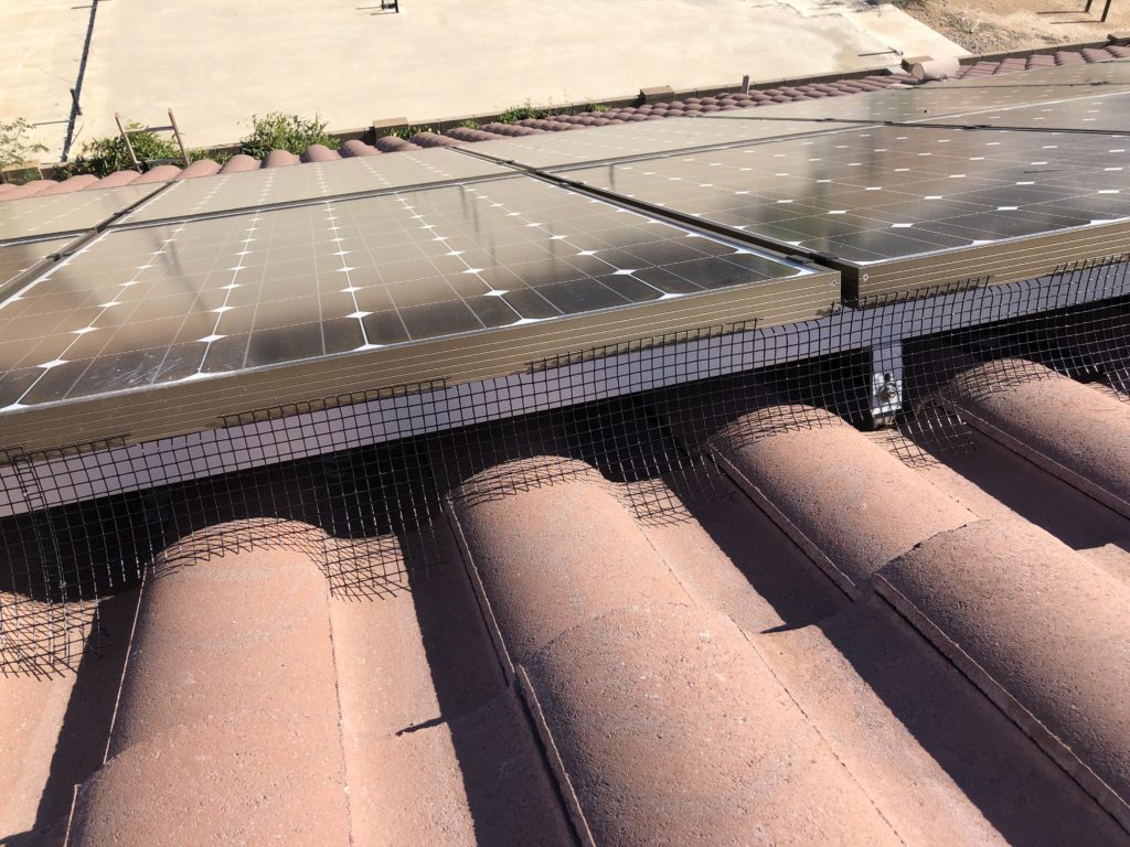 A close up of the pigeon proofing and bird proofing of solar panels on an s-tile rooftop